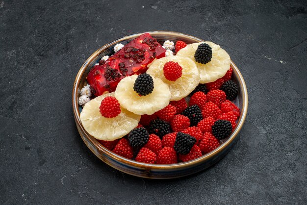 Front view dried pineapple rings with confiture berries on the dark grey surface fruit dry raisin sweet sugar candy