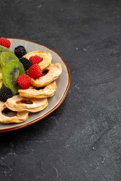 Front view dried pineapple rings with dried kiwis and apples on dark grey surface fruit dry sweet sugar candy