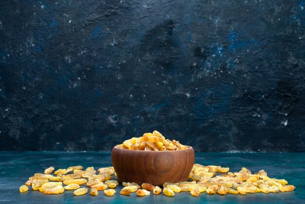 Front view dried raisins inside and outside brown pot on the blue desk.