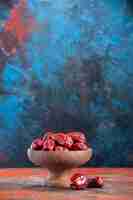 Free photo front view dried red jujubes inside wooden plate on dark blue background spring holiday horizontal sour dry