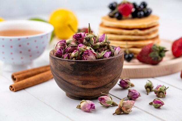 Front view dried rose buds with a cup of tea and cinnamon