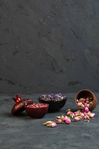 Front view dried roses in vases with scattered pink dried roses