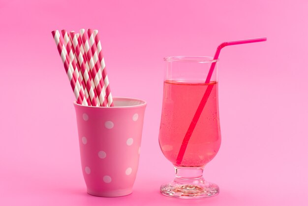 A front view drink and candies pink,-white, stick candies with juice on pink, sugar sweet color