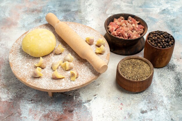 Front view dushbara dough rolling-pin on dough pastry board bowls with meat pepper egg yolk on nude background