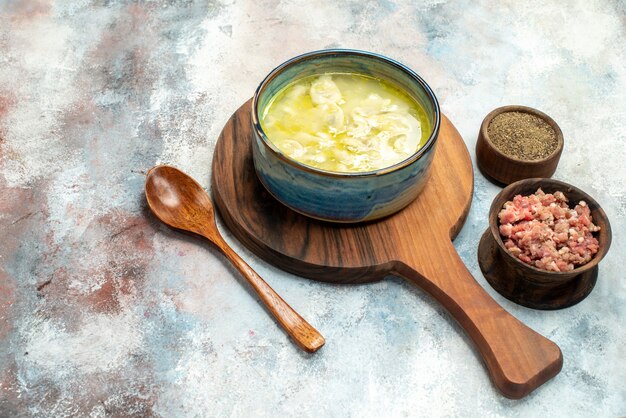 Front view dushbara dumplings soup on cutting board bowls with meat and pepper a wooden spoon on nude background