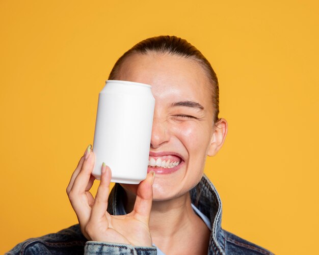 Front view of ecstatic woman with soda can covering her eye