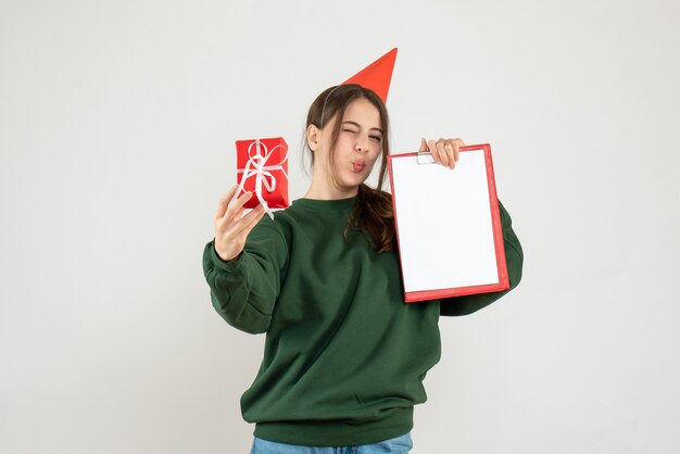 Front view elated girl with party cap holding her xmas gift and document