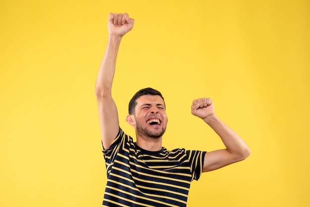 Front view elated handsome man in black and white striped t-shirt yellow isolated background