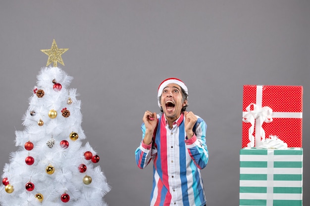 Front view elated man looking up above near white xmas tree