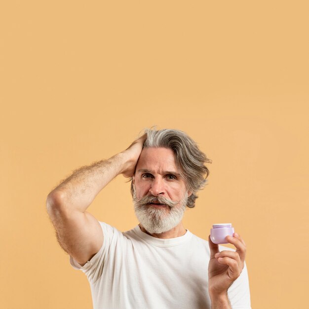 Front view of elder bearded man holding hair gel