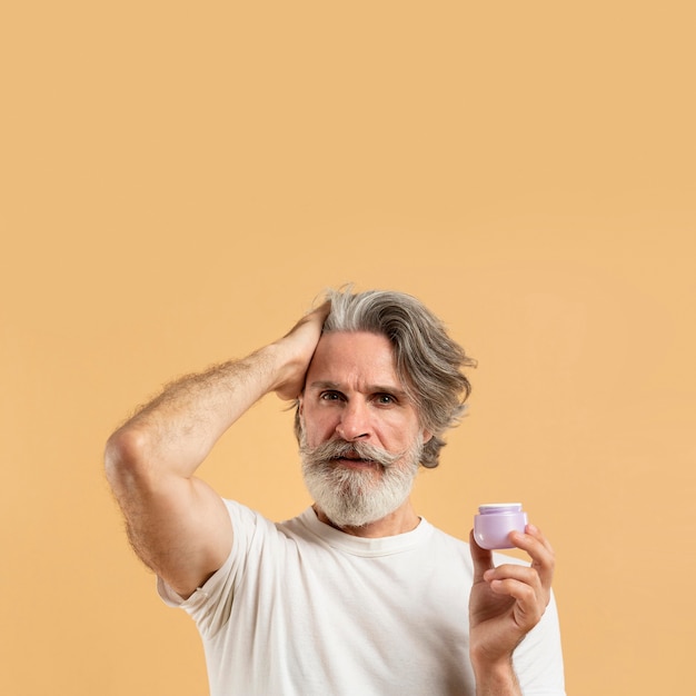 Front view of elder bearded man holding hair gel