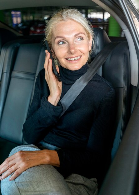 Front view of elder business woman talking the phone in car