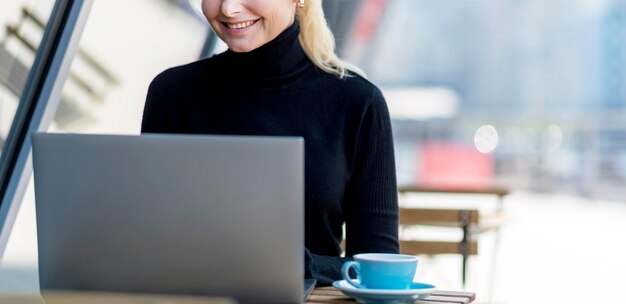 Front view of elder business woman working outdoors on laptop