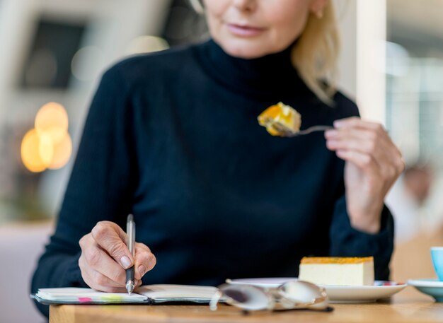 Front view of elder business woman working while having dessert