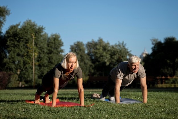 Front view of elder couple doing yoga outdoors