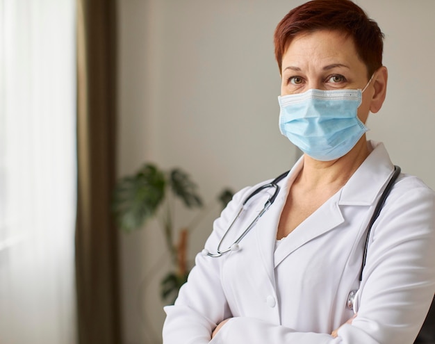 Vista frontale del medico femminile del centro di recupero covid anziano con mascherina medica