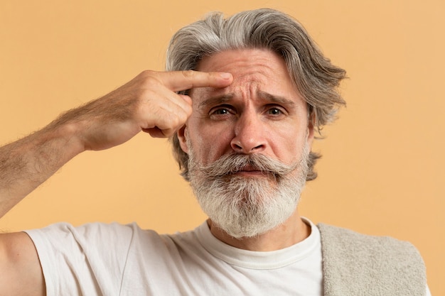 Front view of elder man with beard pointing out wrinkles