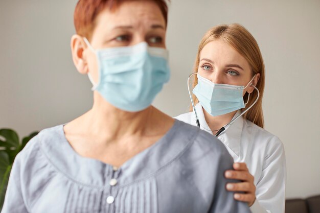 청진기와 의료 마스크와 covid 복구 센터 여성 의사와 노인 환자의 전면보기