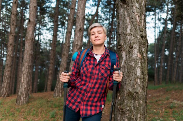 Front view of elder tourist woman posing in the forest