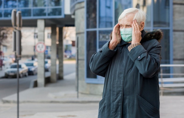 Free photo front view of elder woman in the city wearing a medical mask