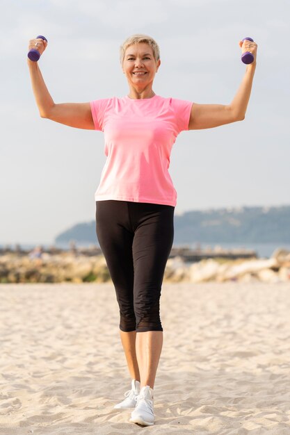 Front view of elder woman holding up weights while working out