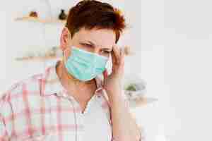 Free photo front view of elder woman with medical mask not feeling well