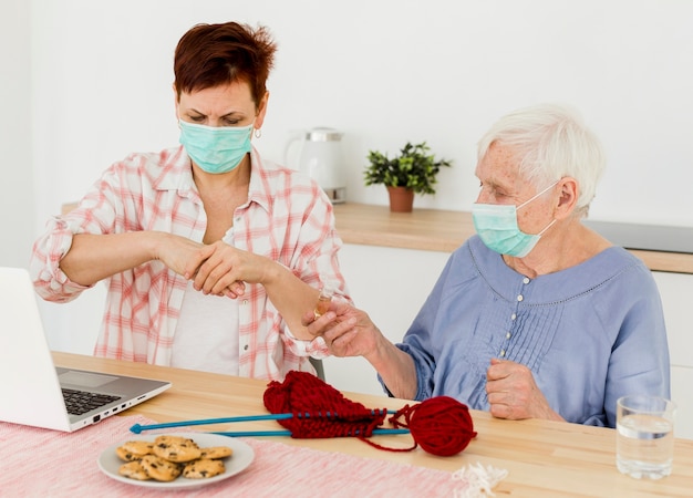 Vista frontale delle donne anziane che disinfettano le loro mani a casa