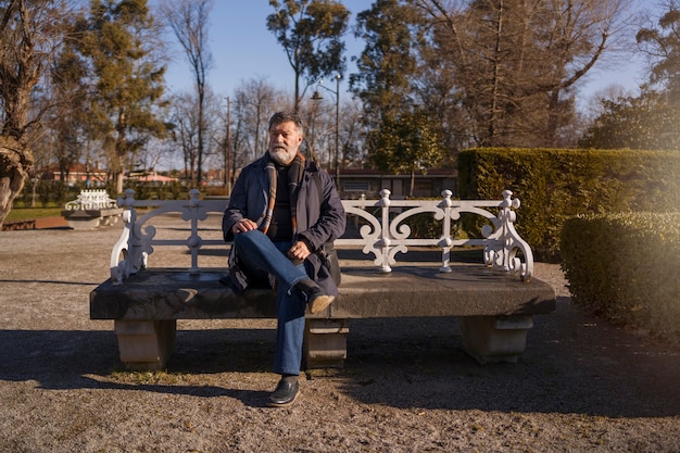 Free photo front view elderly man sitting on bench