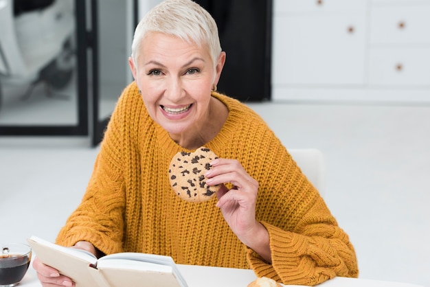 大きなクッキーを押しながら笑みを浮かべて高齢女性の正面図