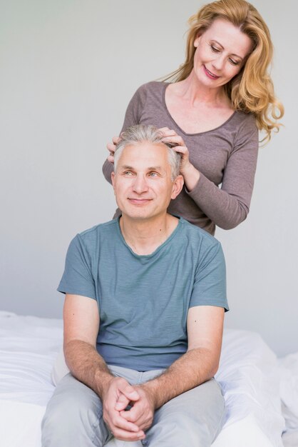 Front view elderly woman touching husbands hair