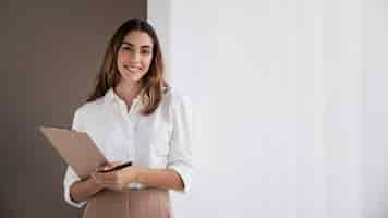 Free photo front view of elegant businesswoman holding clipboard with copy space