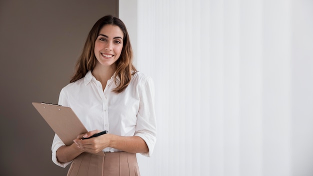 Front view of elegant businesswoman holding clipboard with copy space