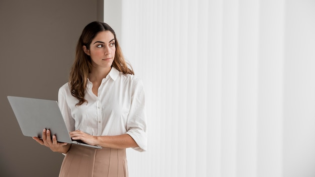 Front view of elegant businesswoman holding laptop with copy space