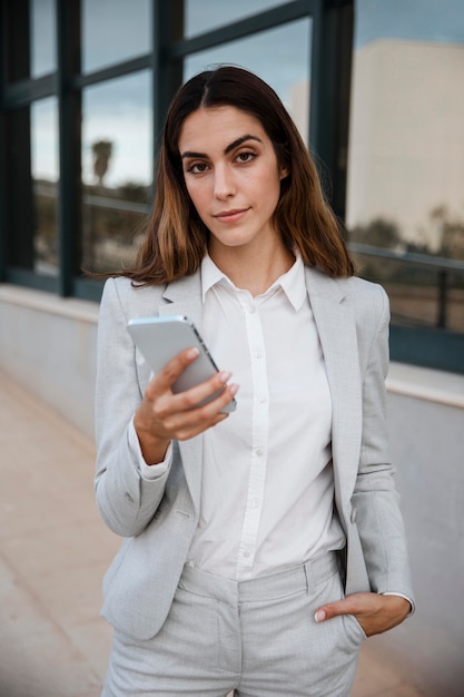 Free photo front view of elegant businesswoman holding smartphone in the city