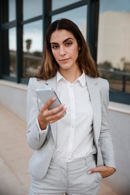 Front view of elegant businesswoman holding smartphone in the city