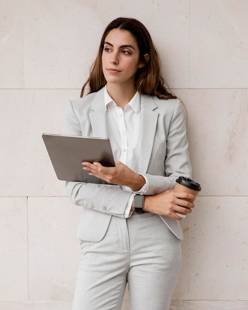 Front view of elegant businesswoman holding tablet and coffee cup