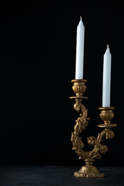 Free photo front view of elegant candlestick with white candles on dark