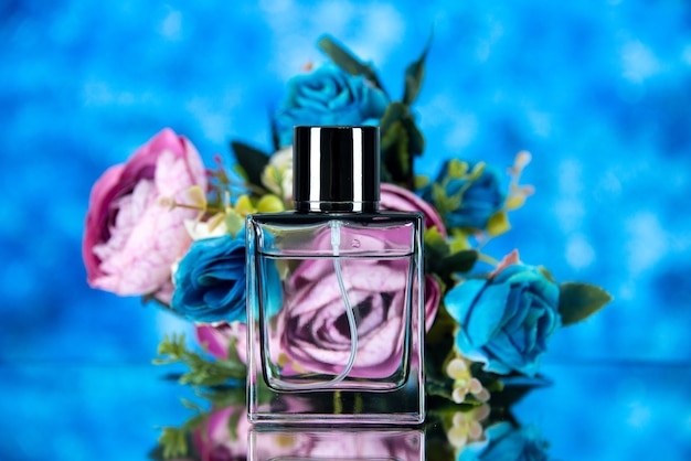 Front view of elegant perfume bottle and colored flowers on brown background