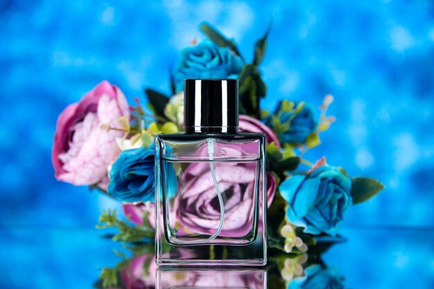 Front view of elegant perfume bottle and colored flowers on brown background