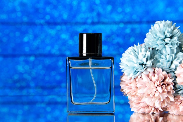 Free photo front view of elegant perfume and colored flowers on blue background