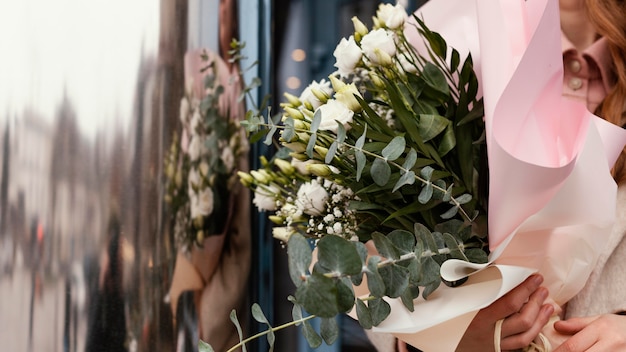 Front view of elegant woman outdoors holding a bouquet of flowers