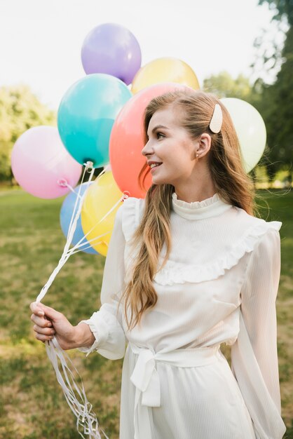 Вид спереди элегантная молодая женщина с воздушными шарами