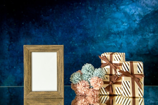 Free photo front view empty picture frame valentines day presents flowers on dark blue abstract background free space