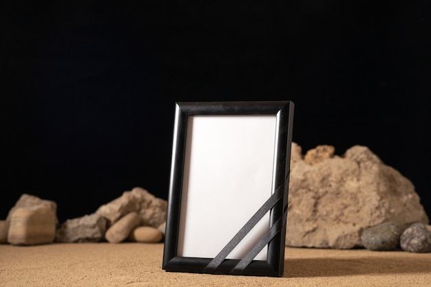 Front view of empty picture frame with different stones on dark