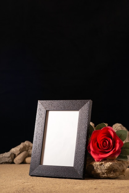 Free photo front view of empty picture frame with red flower and stones on black