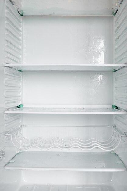 Вид спереди на пустой холодильник, остающийся дома Белый современный морозильник без овощей и фруктов в доме Электрический холодильник с несколькими полками Концепция прибора и охладителя