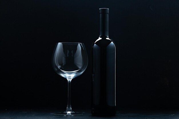 暗い背景色のワインアルコールお祝いホリデーレストランにワインのボトルと正面の空のワイングラス