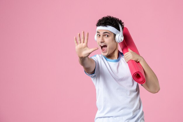 Front view excited young male in sport clothes with yoga mat