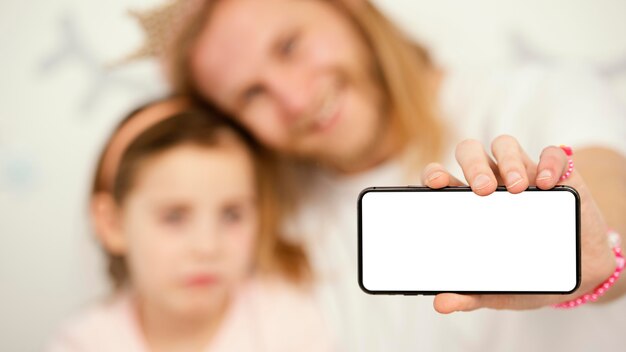 Front view of father and daughter holding smartphone with copy space