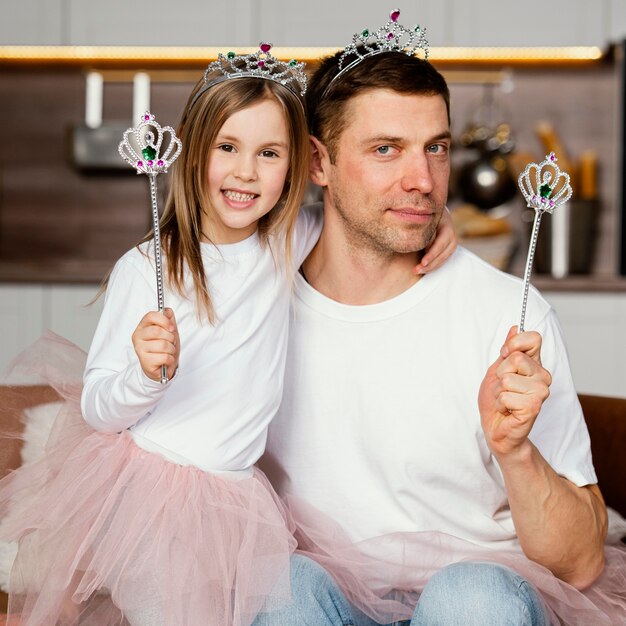 Front view of father and daughter playing with tiara and wand